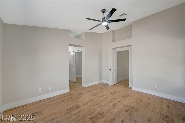 unfurnished bedroom featuring light wood-type flooring, visible vents, lofted ceiling, and baseboards