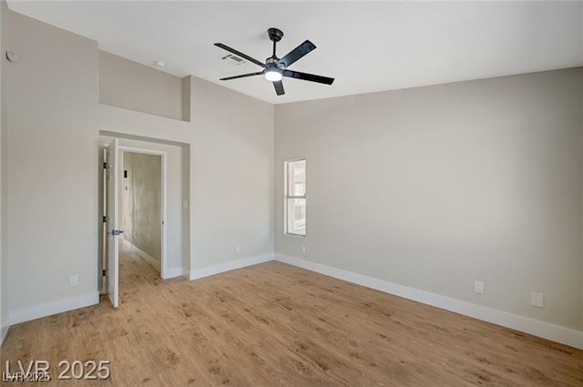 spare room with vaulted ceiling, ceiling fan, light wood-style flooring, baseboards, and visible vents