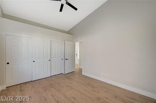unfurnished bedroom featuring baseboards, high vaulted ceiling, and wood finished floors
