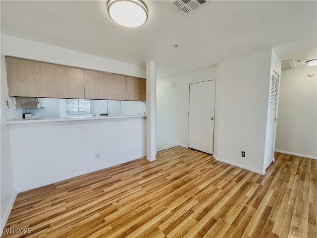 interior space featuring baseboards, light wood-style floors, and visible vents