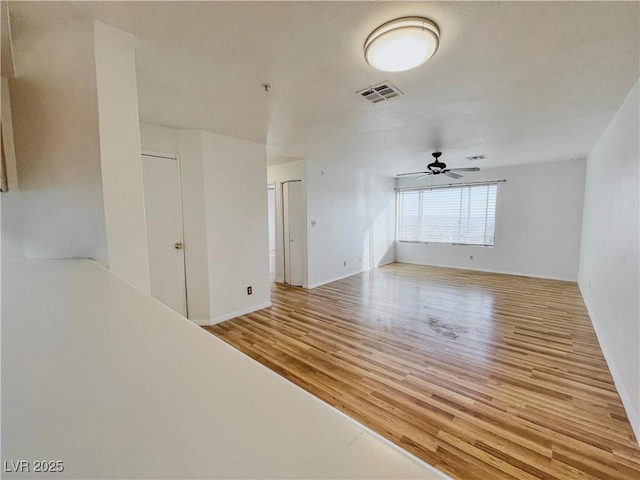 empty room with baseboards, wood finished floors, visible vents, and ceiling fan