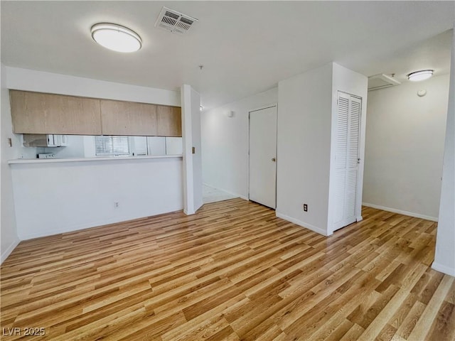 unfurnished living room with baseboards, visible vents, and light wood-style floors