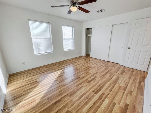 unfurnished bedroom featuring light wood-style flooring, visible vents, a closet, and a ceiling fan