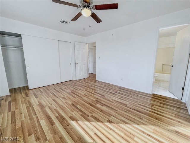 unfurnished bedroom featuring ensuite bath, visible vents, light wood-style floors, and a ceiling fan