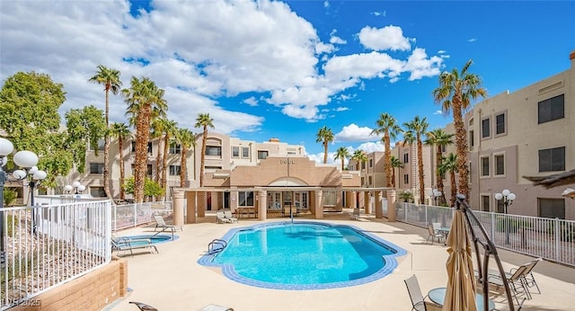 community pool with fence, a residential view, and a patio