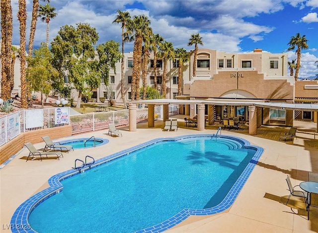 pool with a community hot tub, a patio, and fence