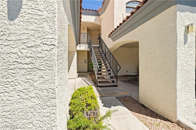 view of home's exterior featuring stairway, a tile roof, and stucco siding