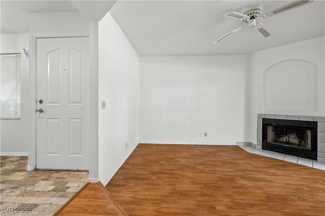 unfurnished living room featuring ceiling fan, baseboards, wood finished floors, and a tile fireplace