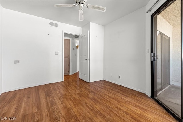 unfurnished bedroom with wood finished floors, visible vents, baseboards, and ceiling fan