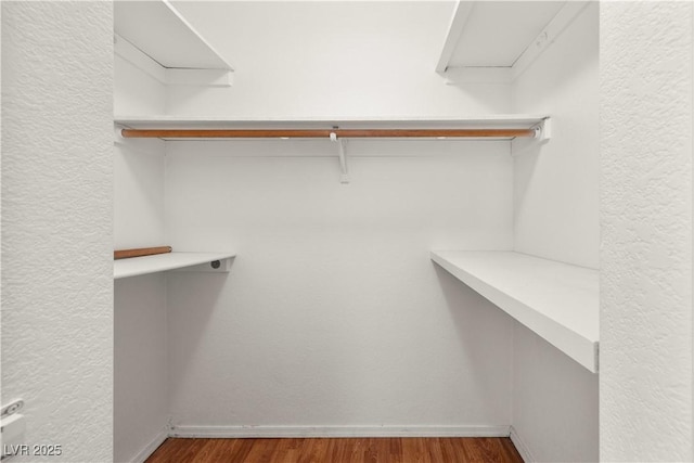 spacious closet with attic access and wood finished floors