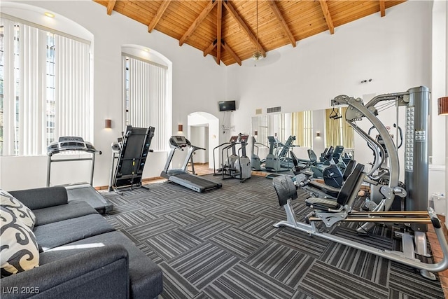 gym featuring arched walkways, high vaulted ceiling, wooden ceiling, and carpet
