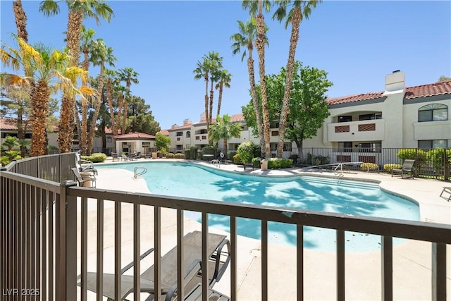 community pool with a residential view, a patio, and fence