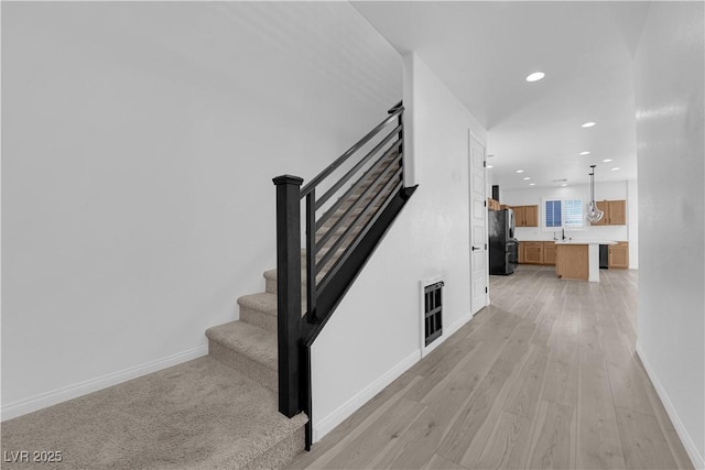 stairs with recessed lighting, wood finished floors, and baseboards