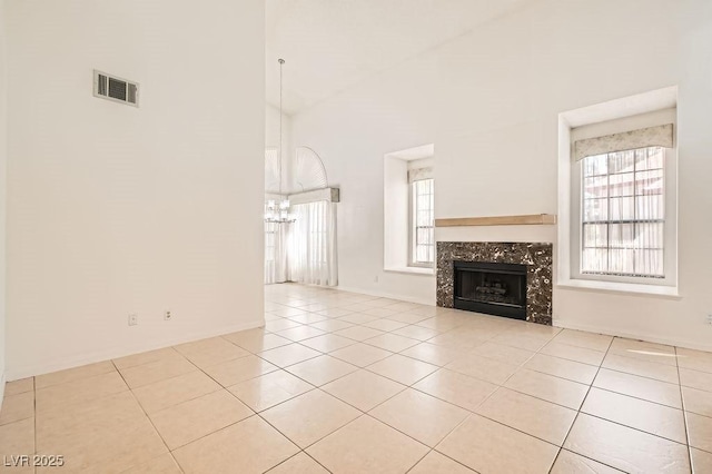 unfurnished living room featuring visible vents, an inviting chandelier, a healthy amount of sunlight, and light tile patterned floors