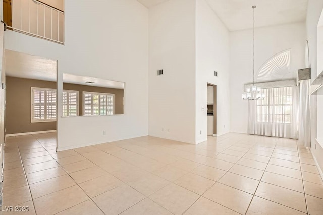 unfurnished living room with visible vents, a towering ceiling, an inviting chandelier, and light tile patterned flooring