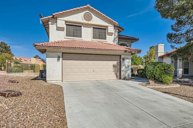 mediterranean / spanish-style house with a tile roof, an attached garage, concrete driveway, and fence