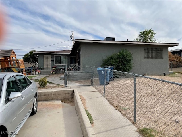 view of front of property featuring stucco siding, a fenced front yard, and a gate