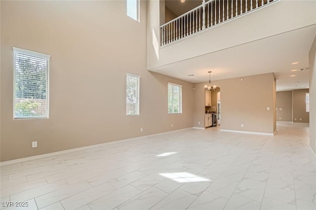3428 Iron Hagen Ct, Las Vegas, NV 89141 - unfurnished living room with marble finish floor, a high ceiling, a notable chandelier, and baseboards