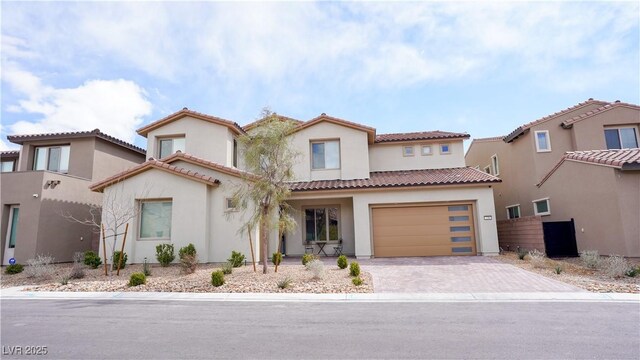mediterranean / spanish-style home with a tiled roof, driveway, and stucco siding