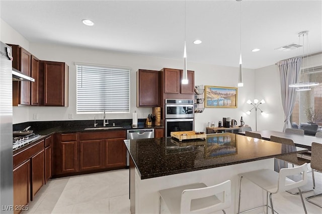 8107 Skye Sweep St, Las Vegas, NV 89166 - kitchen featuring dark stone counters, a sink, stainless steel appliances, a breakfast bar, and visible vents