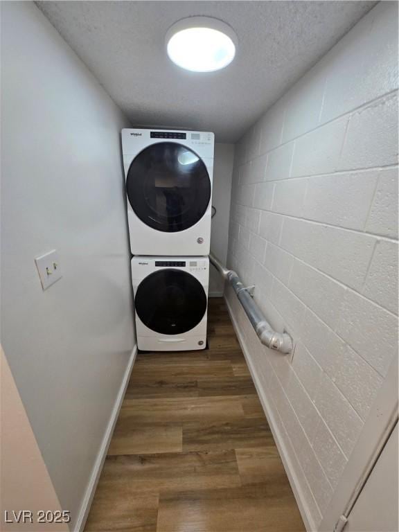 4754 Marnell Dr, Las Vegas, NV 89121 - laundry area with wood finished floors, stacked washer / dryer, laundry area, baseboards, and concrete block wall