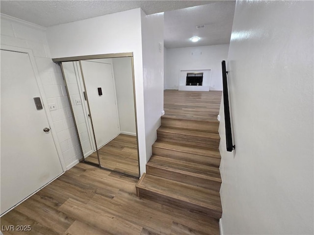 4754 Marnell Dr, Las Vegas, NV 89121 - staircase with a fireplace with raised hearth, wood finished floors, visible vents, and a textured ceiling
