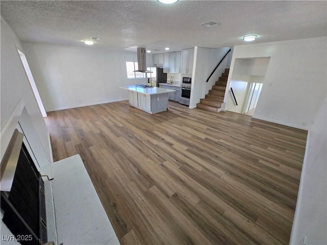 4754 Marnell Dr, Las Vegas, NV 89121 - unfurnished living room featuring wood finished floors, a textured ceiling, stairs, baseboards, and visible vents