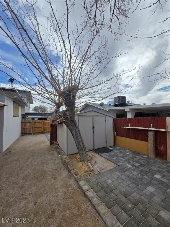 4754 Marnell Dr, Las Vegas, NV 89121 - view of patio featuring a storage unit, an outbuilding, a fenced backyard, and central AC unit
