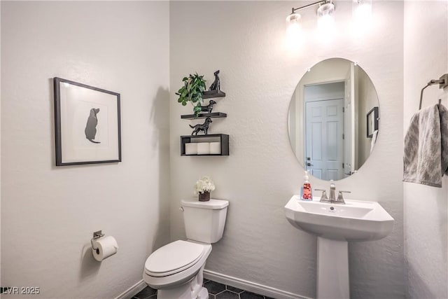 half bathroom with tile patterned floors, toilet, baseboards, and a sink