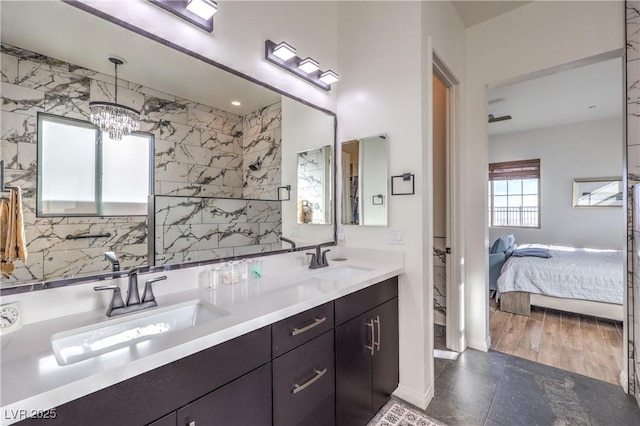 full bathroom featuring ensuite bathroom, a sink, a notable chandelier, and double vanity