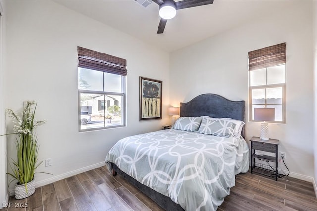bedroom with baseboards, a ceiling fan, wood finished floors, and multiple windows