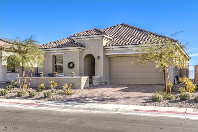mediterranean / spanish home featuring a garage, a tile roof, stucco siding, and driveway