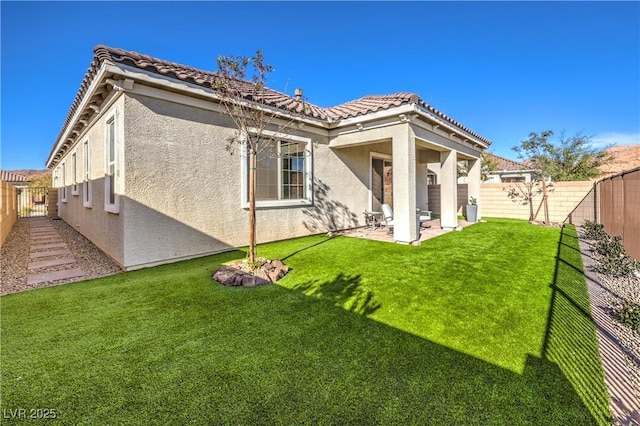 back of property featuring a fenced backyard, a tiled roof, and stucco siding