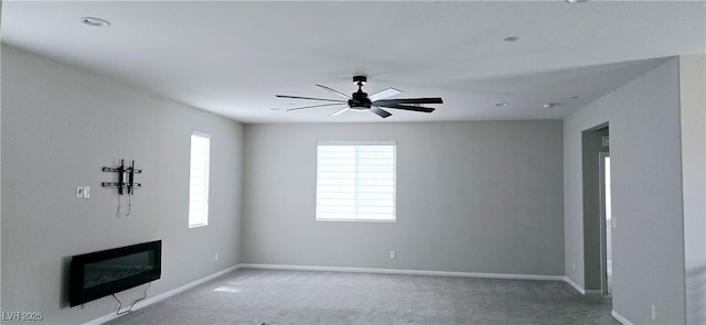 26 Lilla Rosa St, Henderson, NV 89011 - unfurnished living room featuring a glass covered fireplace, a ceiling fan, carpet flooring, and baseboards