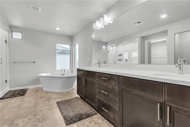 bathroom with baseboards, a stall shower, double vanity, healthy amount of natural light, and recessed lighting