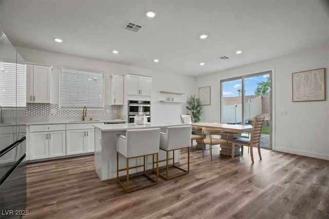 kitchen featuring white cabinets, stainless steel double oven, visible vents, and a sink