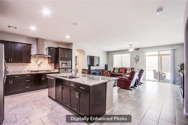 10470 Irish Cliffs Ct, Las Vegas, NV 89149 - kitchen featuring a sink, visible vents, stainless steel appliances, arched walkways, and wall chimney exhaust hood
