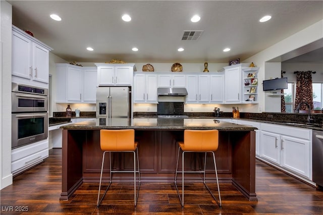 kitchen with stainless steel appliances, a sink, visible vents, open shelves, and under cabinet range hood