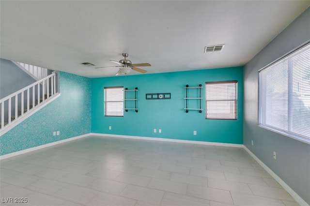 spare room featuring a wealth of natural light, visible vents, stairs, and ceiling fan