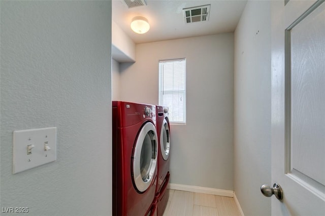 washroom featuring washer and dryer, baseboards, laundry area, and visible vents