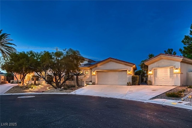 view of property hidden behind natural elements featuring a garage, solar panels, stucco siding, and driveway