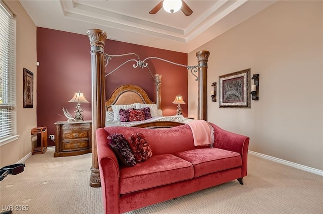 carpeted bedroom featuring baseboards, a raised ceiling, and a ceiling fan