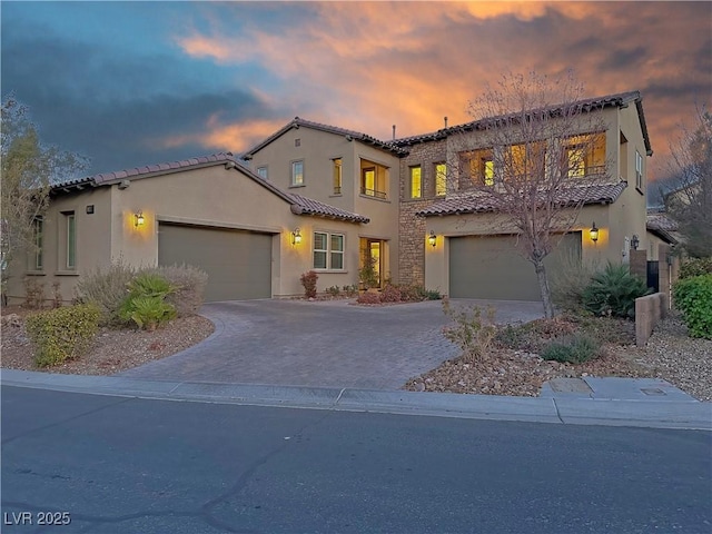 mediterranean / spanish-style home featuring driveway, a tiled roof, and stucco siding