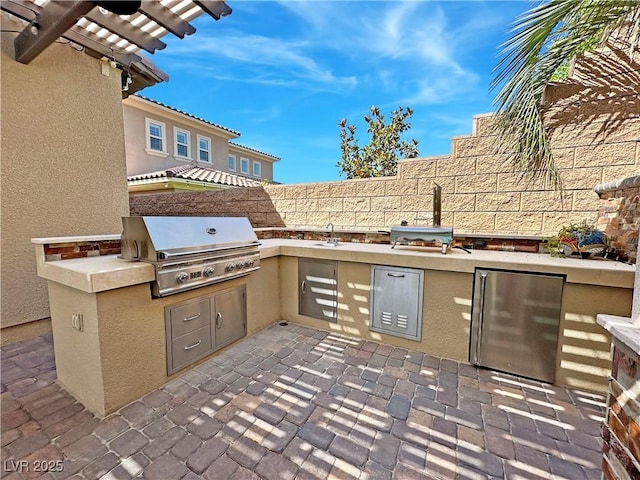 view of patio featuring a grill, an outdoor kitchen, fence, and a sink