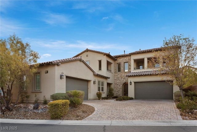 mediterranean / spanish-style home featuring stone siding, a tiled roof, and stucco siding
