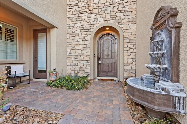 view of exterior entry with stone siding and stucco siding