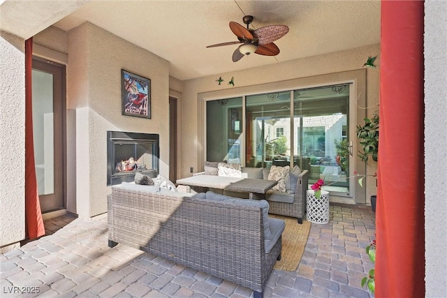 view of patio / terrace with an outdoor living space with a fireplace and ceiling fan