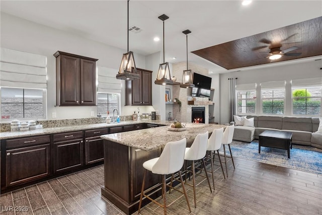 kitchen featuring dark wood-style floors, a breakfast bar, a sink, dark brown cabinetry, and open floor plan