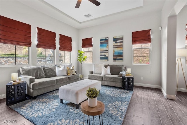 living area with ceiling fan, a wealth of natural light, wood finished floors, and visible vents