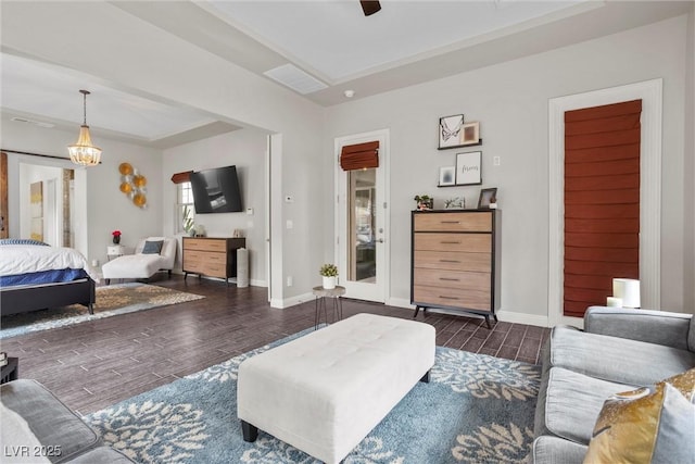 living room featuring ceiling fan with notable chandelier, baseboards, wood finished floors, and visible vents